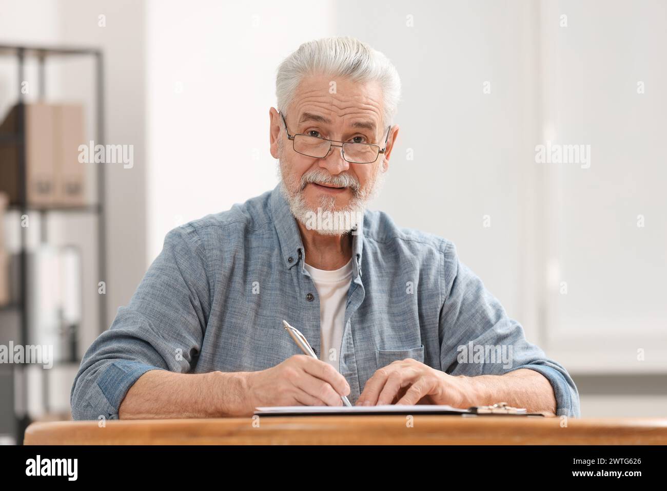 Homme senior signant dernier testament et testament à table à l'intérieur Banque D'Images