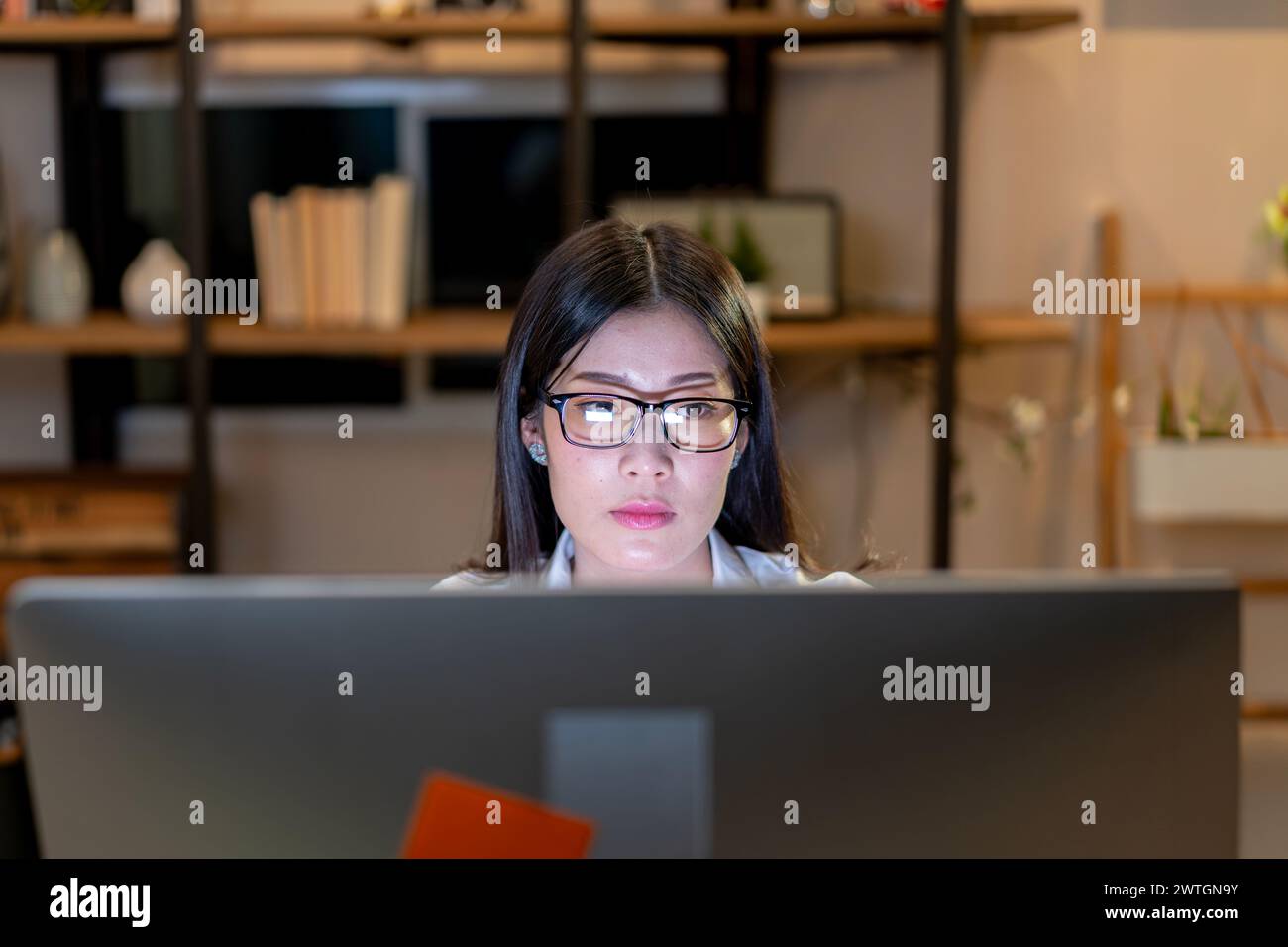 La jeune femme est assise et regarde l'écran de l'ordinateur Banque D'Images