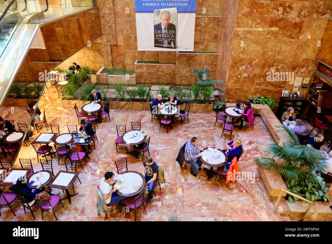 Atrium pompeux de Trump Tower, des gens assis dans un café avec des escaliers mécaniques à côté d'eux, superposés par une affiche, Manhattan, New York City, New York Banque D'Images