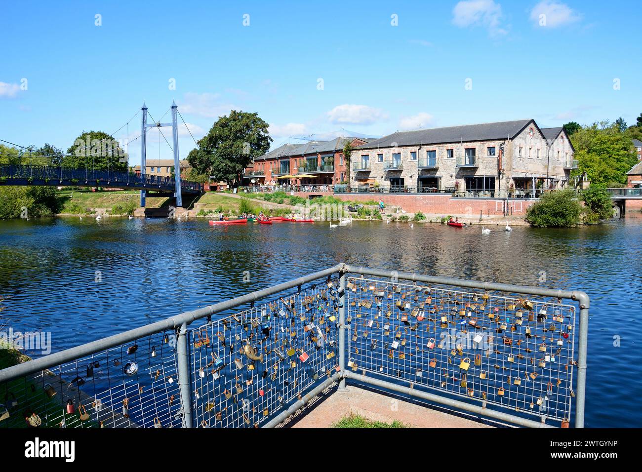 Vue sur le pont suspendu Cricklepit au-dessus de la rivière Exe avec des lovelocks sur des rampes au premier plan et restaurant de quai à l'arrière, Exeter, Royaume-Uni. Banque D'Images