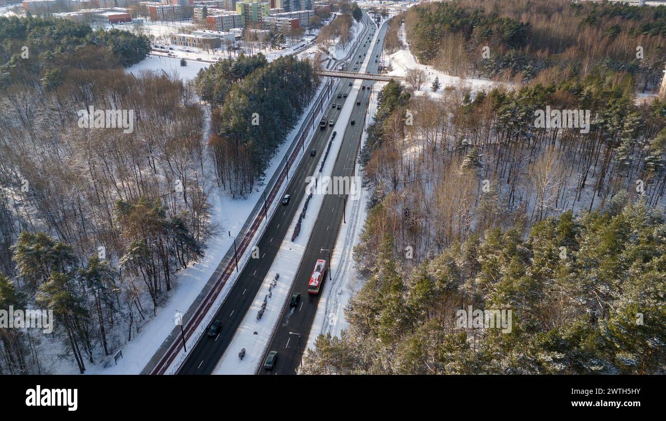 Photographie par drone du parc forestier public, route avec circulation et vieilles maisons à plusieurs étages pendant la journée ensoleillée d'hiver Banque D'Images