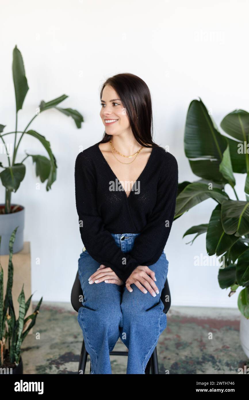 Une fille assise avec un fond lumineux et rempli de plantes Banque D'Images