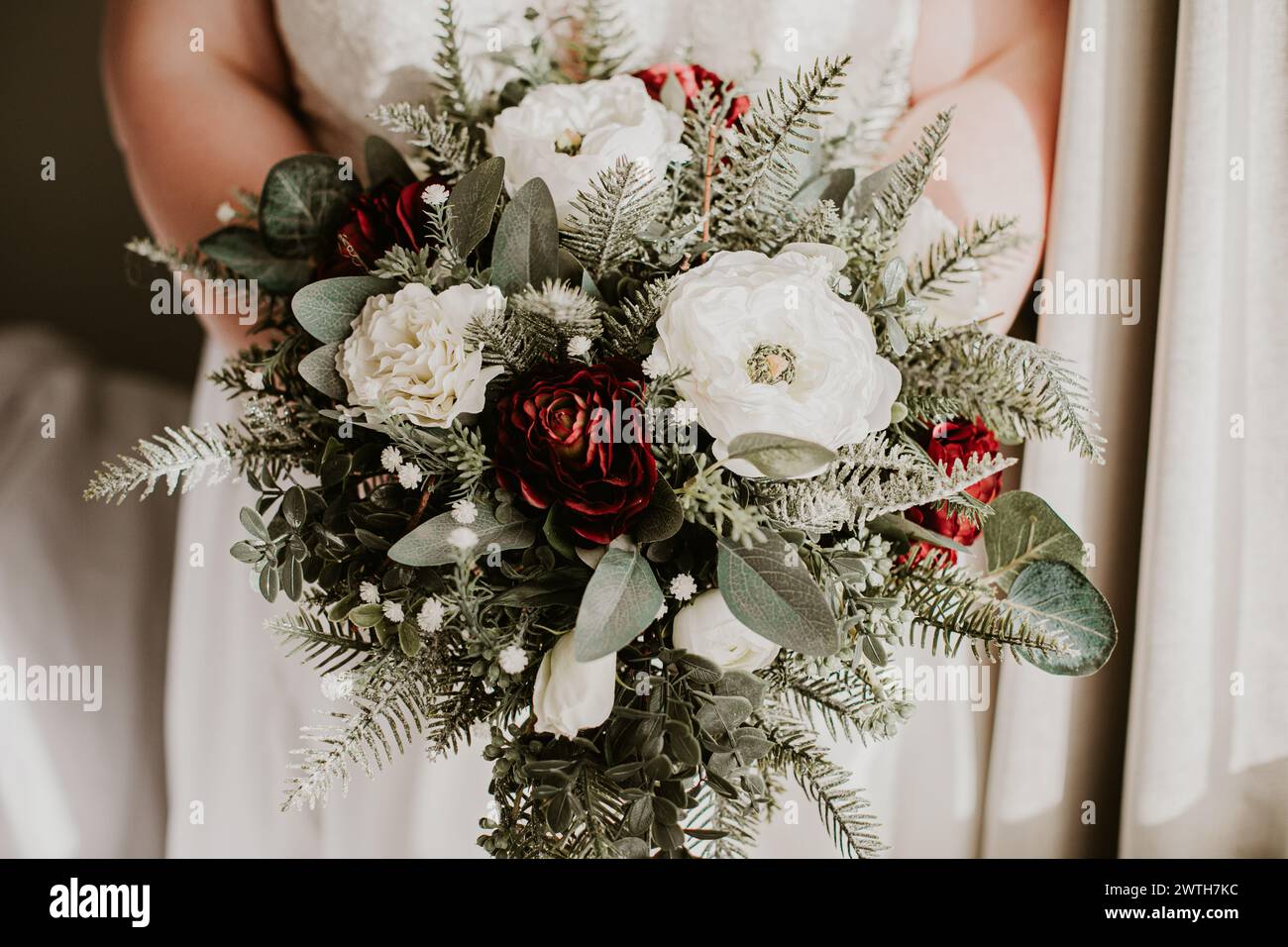 mariée tenant un bouquet de mariage d'hiver avec des fleurs blanches et rouges Banque D'Images