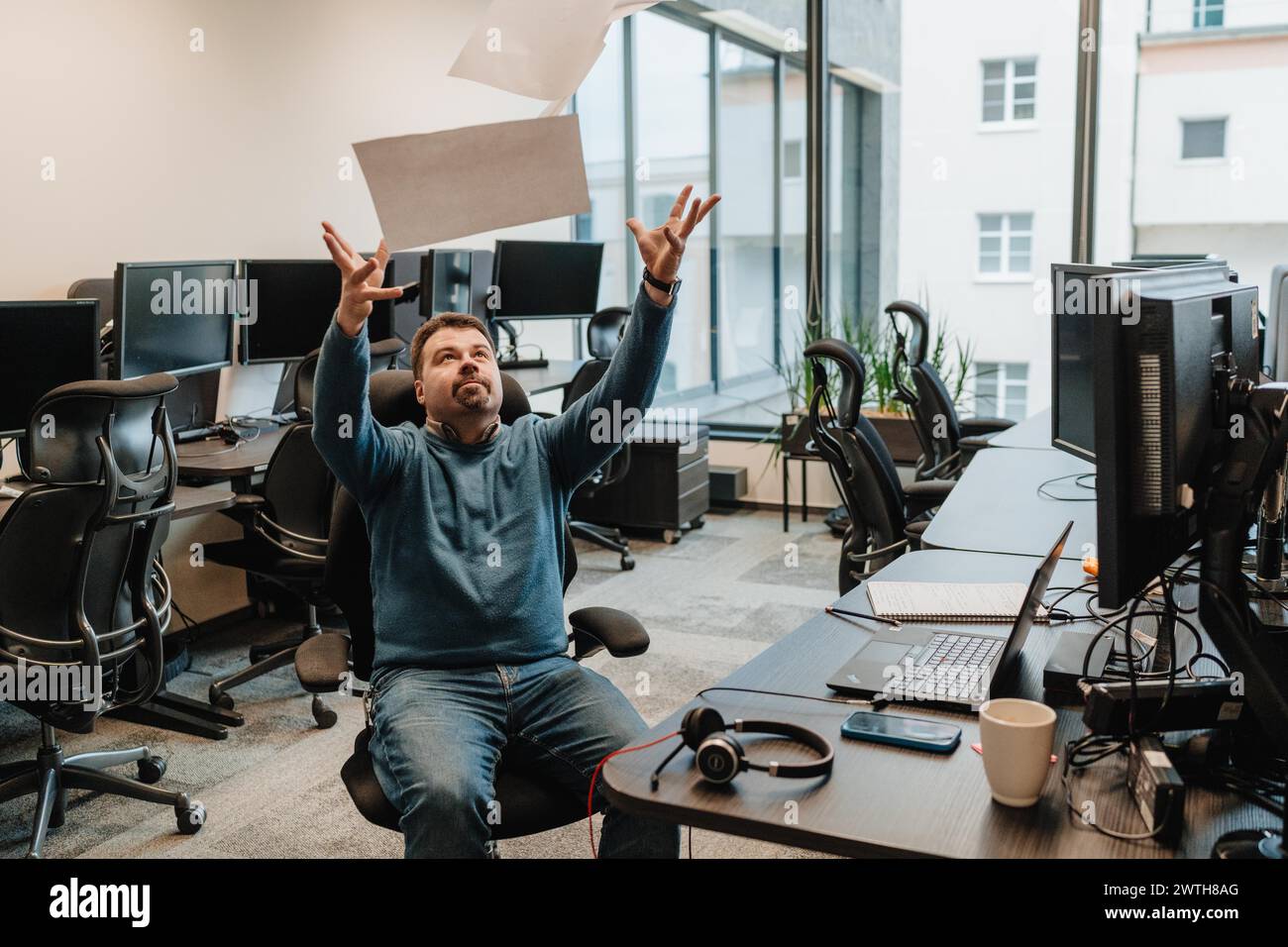 l'homme est fatigué de travailler à l'ordinateur et jette des feuilles de papier Banque D'Images