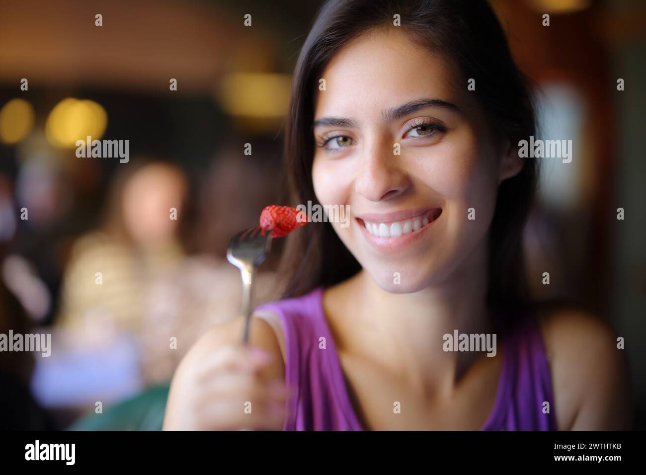 Femme heureuse posant manger de la fraise dans un intérieur de restaurant Banque D'Images