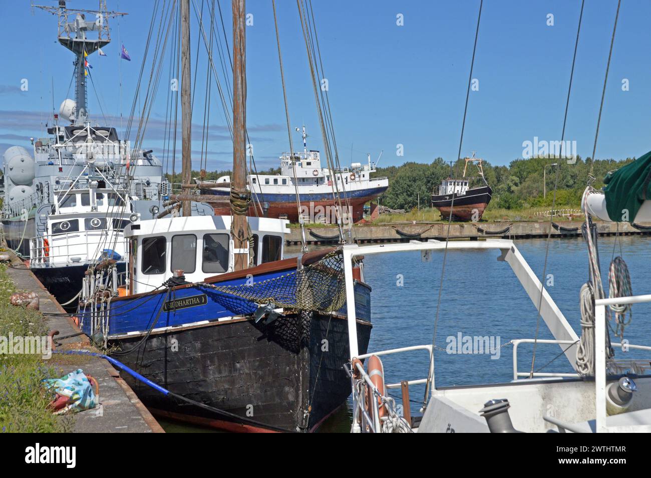 Allemagne, Mecklembourg-Poméranie occidentale, Peenemünde sur l'île d'Usedom : bateaux de pêche, amarrés ou à terre, avec un musée-navire de guerre sur la péninsule. Banque D'Images