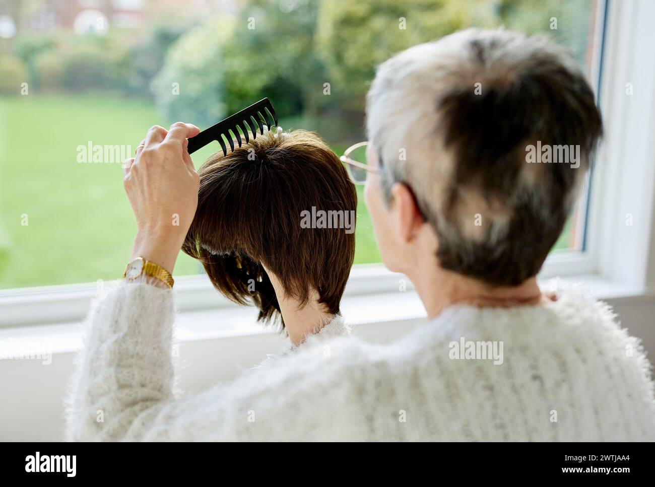 Femme avec alopécie peignant une perruque Banque D'Images