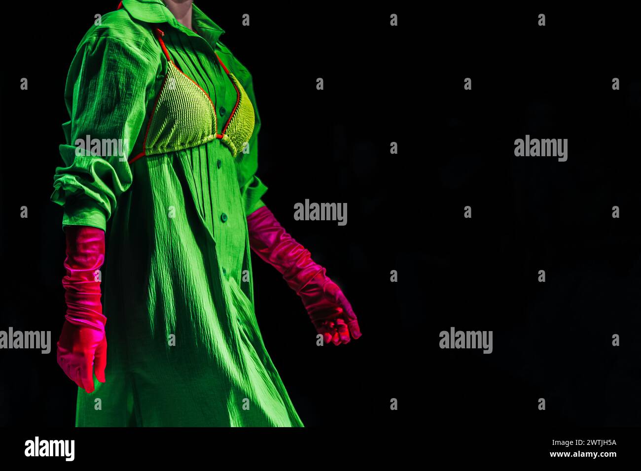 Robe verte créative intéressante tenue lumineuse, gants roses sur fond noir Banque D'Images