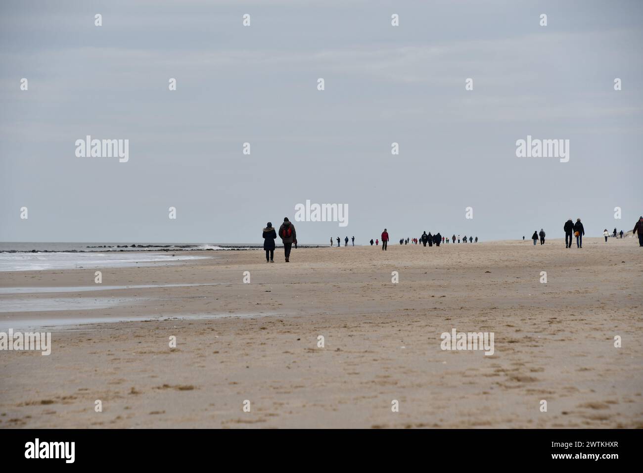 Westerland, Allemagne. 18 mars 2024. Les marcheurs sont en déplacement sur la plage de Westerland sous le ciel couvert lundi. Dans le cadre de l’enquête annuelle sur les plages, les experts de l’île ont vérifié combien de mètres cubes de sable devraient être lavés cette année. Crédit : Lea Sarah Albert/dpa/Alamy Live News Banque D'Images