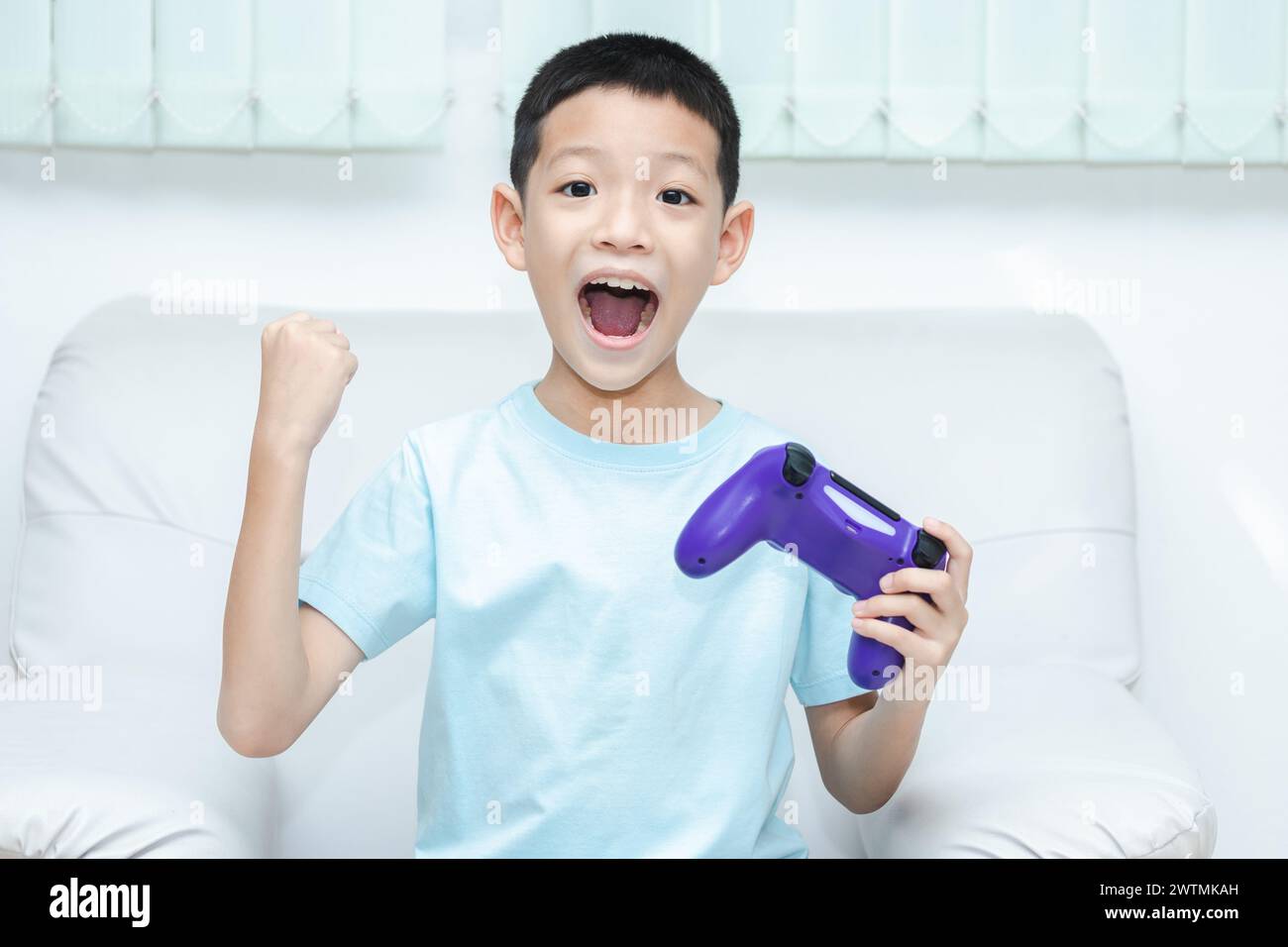 Petit garçon asiatique jouant à un jeu vidéo. plan d'un enfant tenant une manette de jeu. Asian Boy est ravi parce qu'il a gagné et lève les mains joyeusement. Banque D'Images