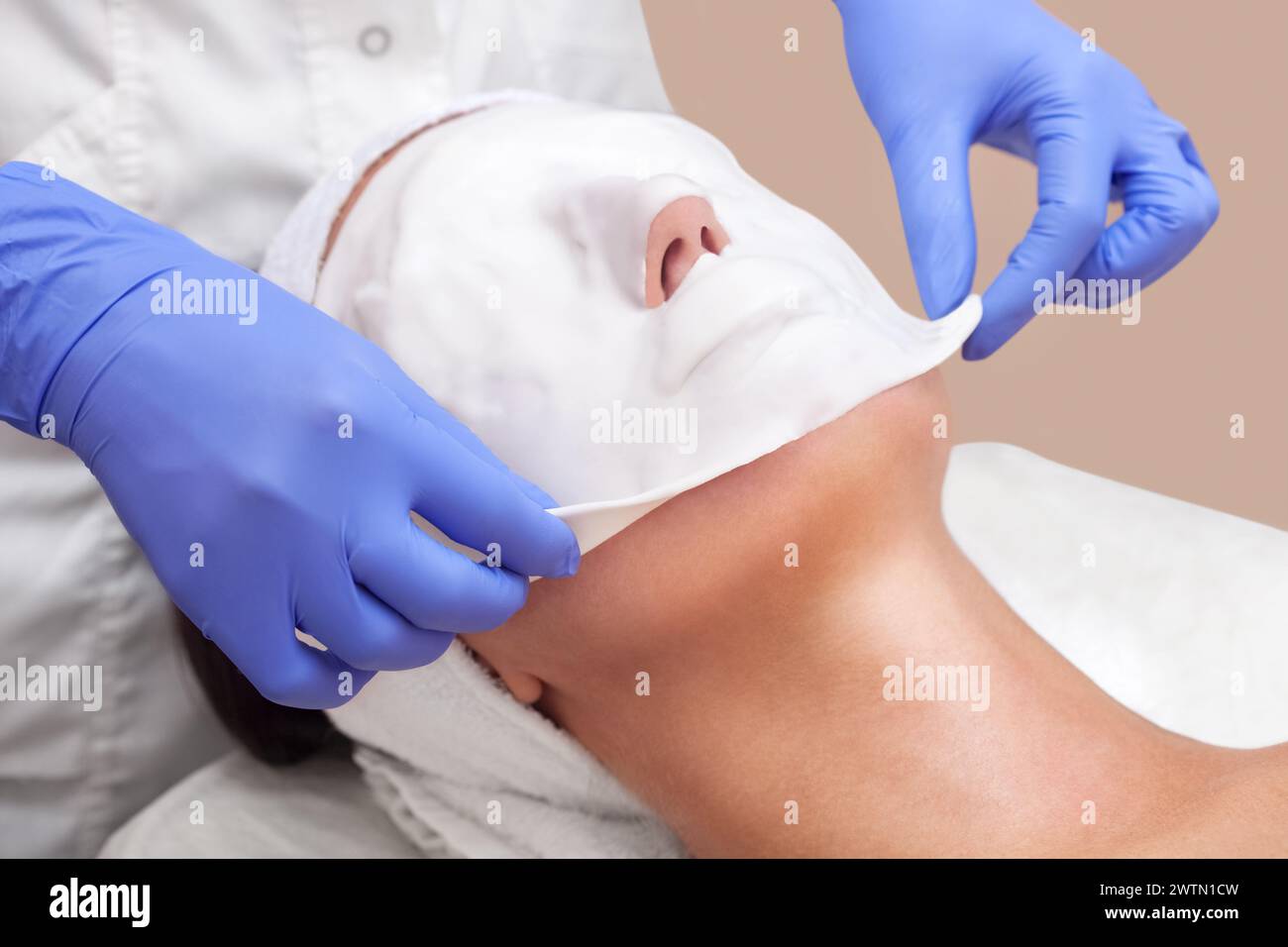 Le cosmétologue pour la procédure de nettoyage et d'hydratation de la peau, en appliquant un masque alginique sur le visage d'une jeune femme dans le salon de beauté.Cosmetolo Banque D'Images