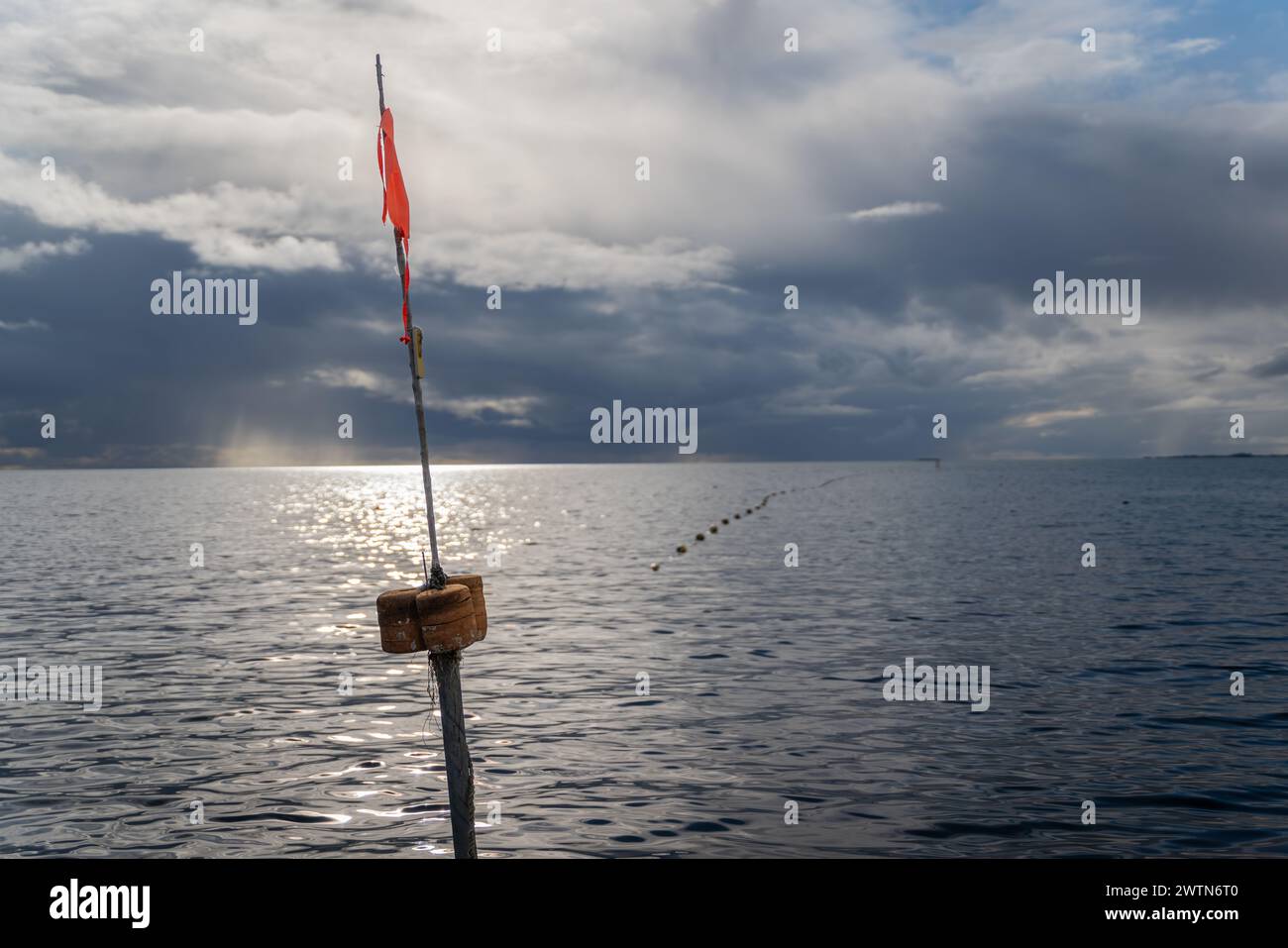 Poteau avec des drapeaux marquant l'emplacement des filets de pêche sous-marins le long du rivage. Filet de pêche, un piège à poissons dans la mer. Soirée d'automne sur la côte Banque D'Images