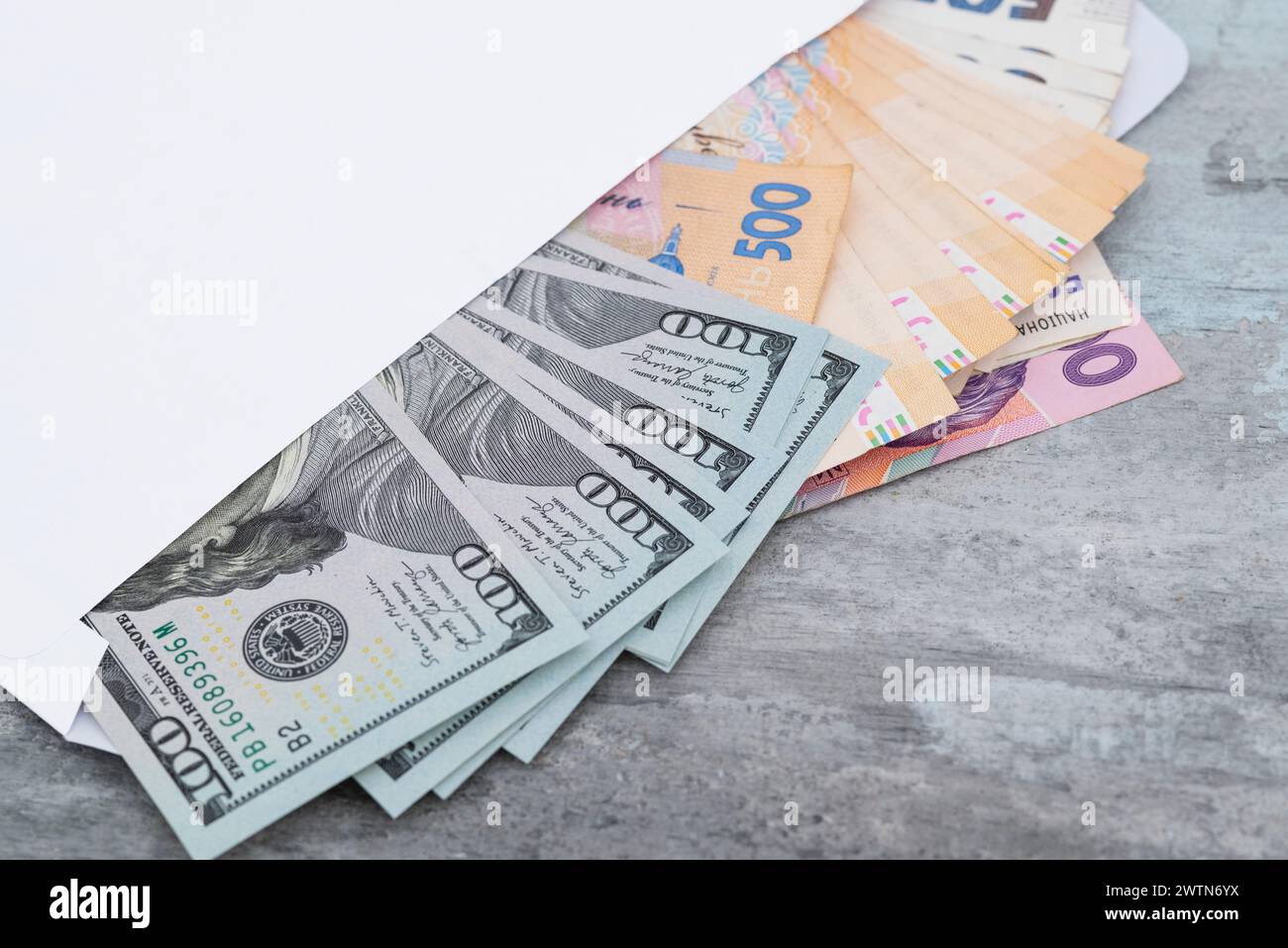 Hryvnias ukrainiennes et dollars américains dans une enveloppe blanche sur un fond de pierre gros plan. Concept de paiement ou de corruption. Banque D'Images