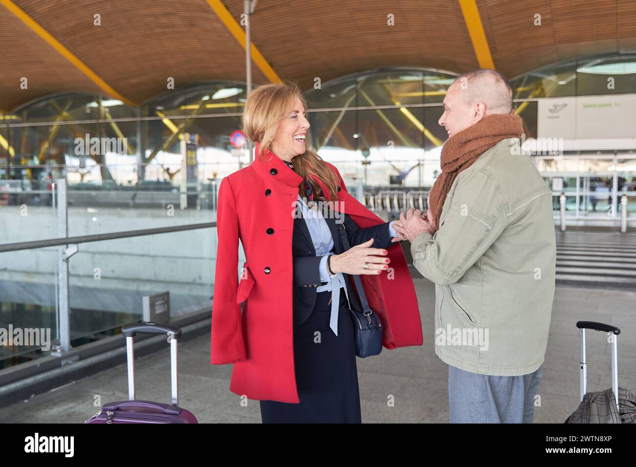 un couple joyeux et mature avec des sourires sur le visage et des valises à la main, prêt à se lancer dans une nouvelle aventure passionnante ensemble à l'aéroport Banque D'Images