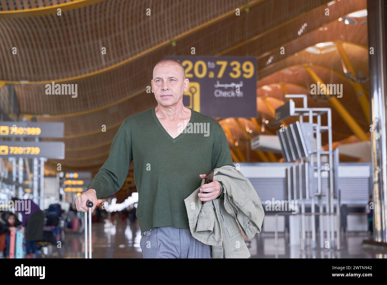 homme d'âge moyen marchant dans l'aéroport avec un sac de voyage Banque D'Images