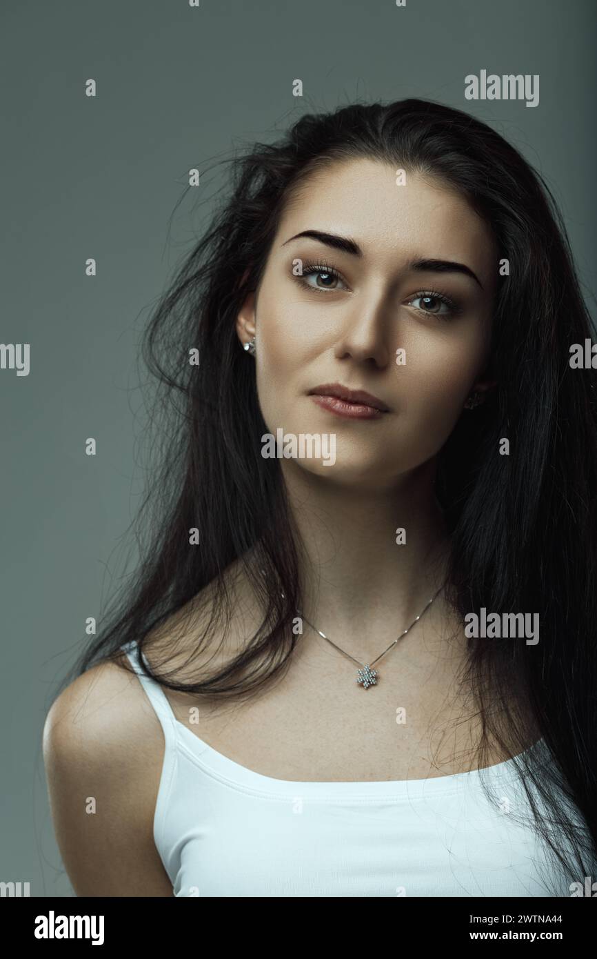 Jeune femme aux yeux perspicaces rayonne de confiance tranquille et d'allure Banque D'Images