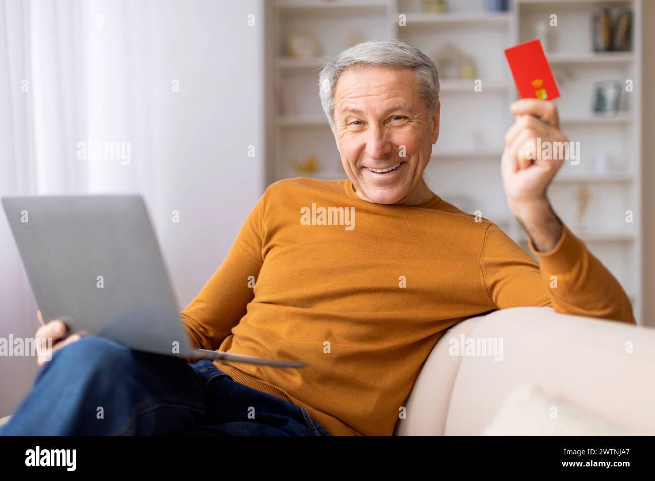 Homme plus âgé avec ordinateur portable et carte de crédit prêt à payer Banque D'Images