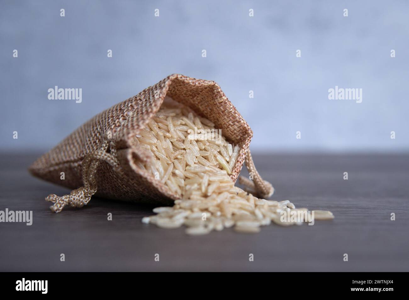 Gros plan image de riz brun dans un petit sac en toile de jute sur une table en bois avec espace de copie. Banque D'Images