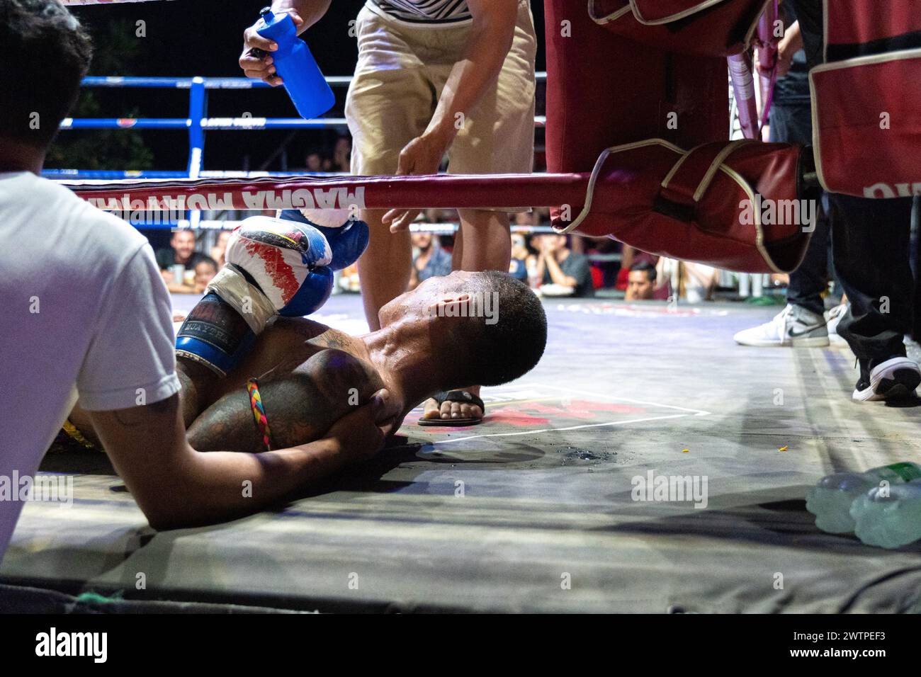 L’entraîneur et une aide donnent de l’eau à son boxeur Petch si Nel, au centre, après un Ko, lors des combats de Muay Thai, sur l’île de Koh Chang, en Thaïlande. Banque D'Images
