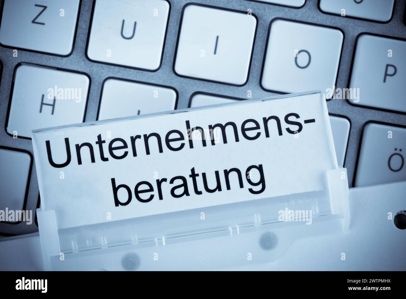 Le dossier d'un dossier suspendu devant un clavier d'ordinateur sur le sujet du conseil en gestion Banque D'Images