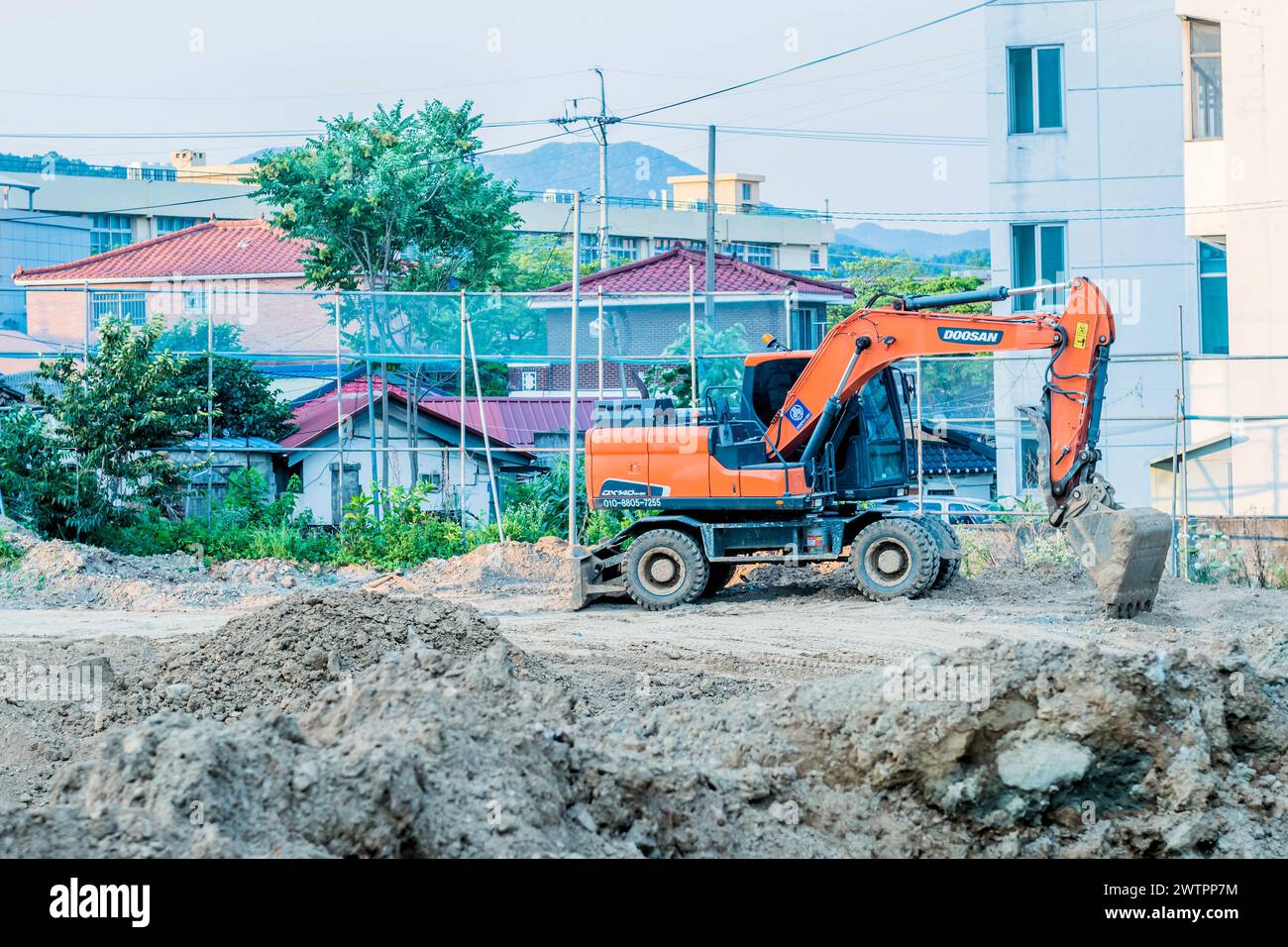 Une excavatrice à l’œuvre dans une zone de construction résidentielle avec des maisons en arrière-plan, à Daejeon, Corée du Sud Banque D'Images