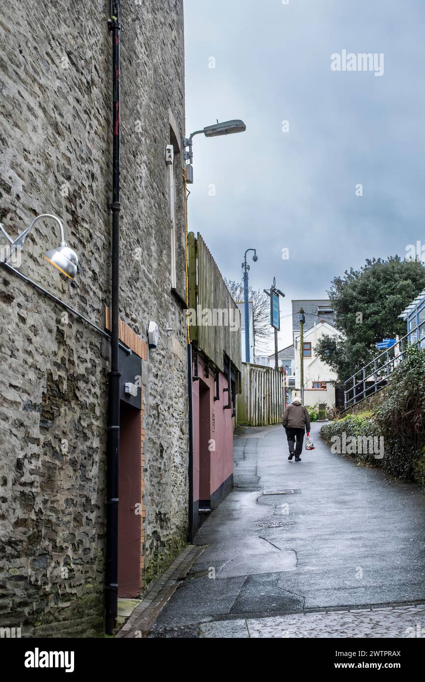 Un homme âgé marchant vers le haut dans une ruelle du centre-ville de Newquay en Cornouailles au Royaume-Uni. Banque D'Images