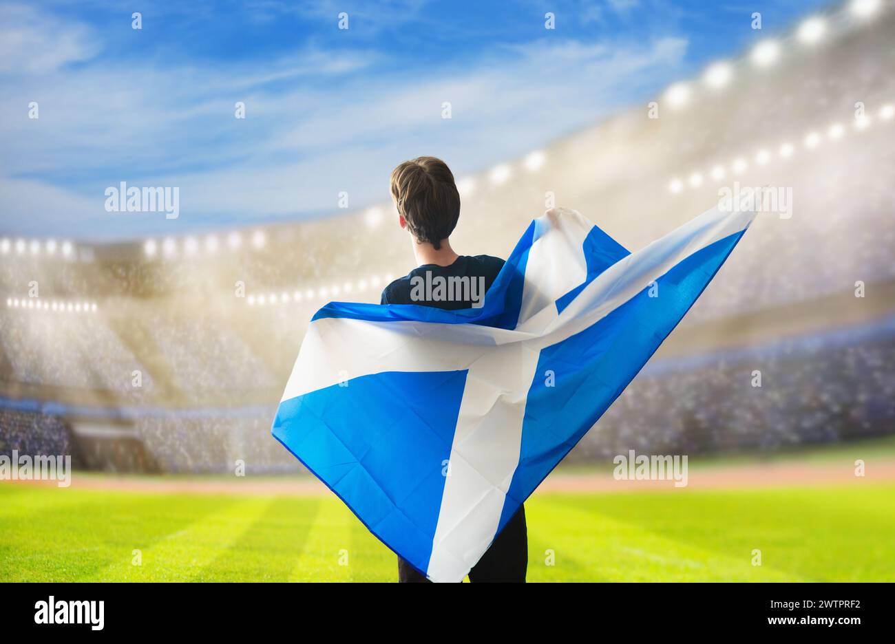 Soutien de football écossais sur le stade. Fans écossais sur un terrain de football regardant l'équipe jouer. Groupe de supporters écossais avec drapeau et maillot national Banque D'Images