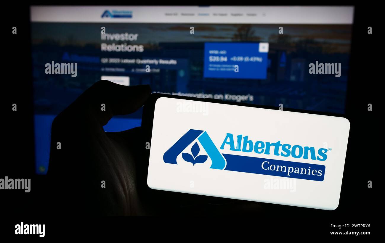 Personne tenant un smartphone avec le logo de la société américaine de vente au détail d'épicerie Albertsons Companies Inc en face du site Web. Concentrez-vous sur l'affichage du téléphone. Banque D'Images