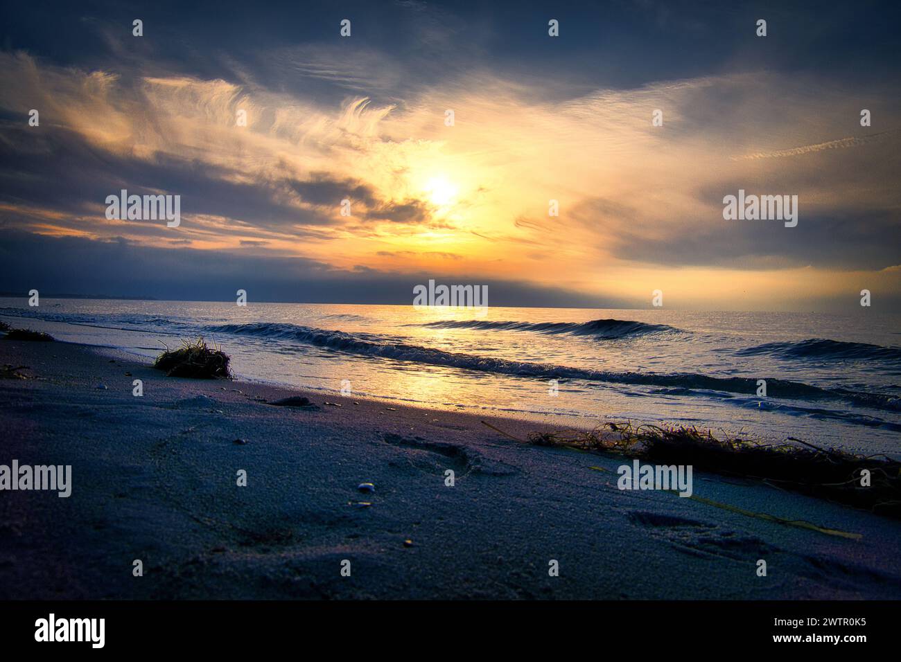 Coucher de soleil, mer illuminée. Plage de sable au premier plan. Ondes lumineuses. Mer Baltique. Paysage sur la côte Banque D'Images