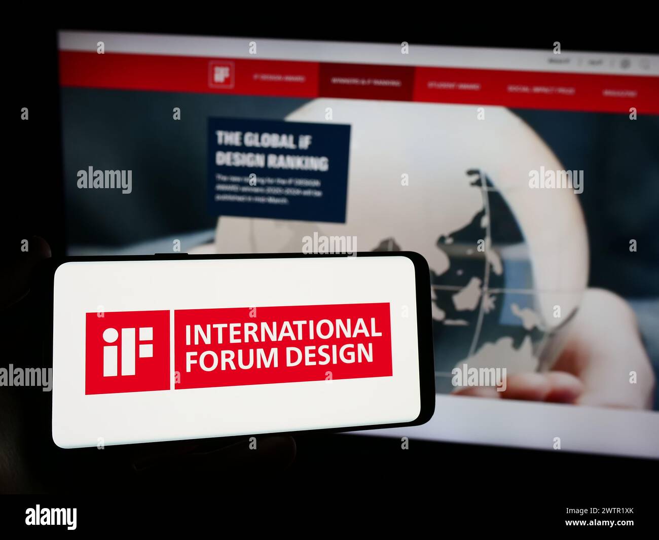Personne tenant un smartphone avec le logo de l'organisation allemande International Forum Design (IF) devant le site. Concentrez-vous sur l'affichage du téléphone. Banque D'Images