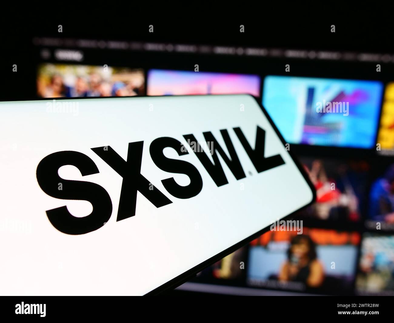 Téléphone portable avec logo de l'événement annuel de film et média South by Southwest (SXSW) devant le site Web. Focus à gauche de l'écran du téléphone. Banque D'Images