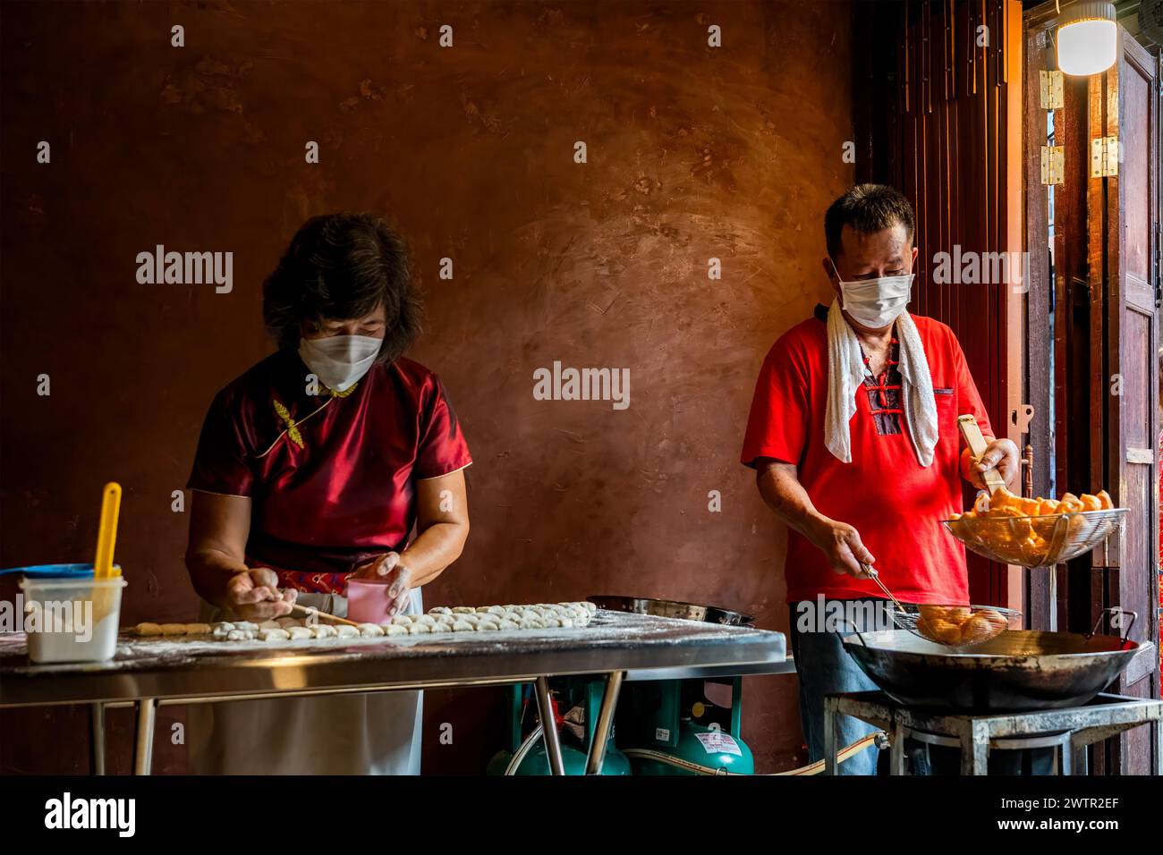 Jomtien, Thaïlande, 10 février 2024 : village chinois de Chakngeaw. Un couple fait youtiao, une longue bande de pâte à farine de blé frite dorée et brune. Banque D'Images