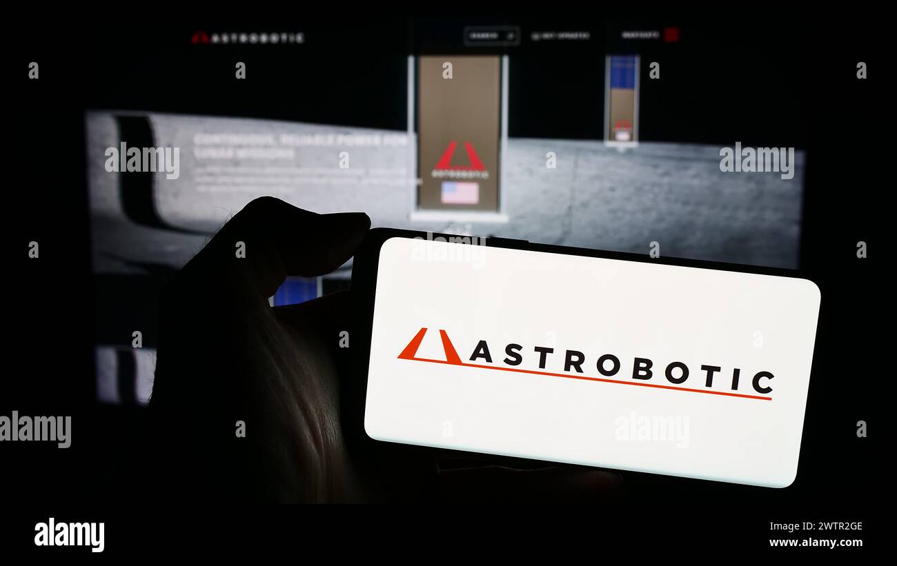 Personne tenant le téléphone portable avec le logo de la société américaine de robotique spatiale Astrobotic Technology Inc en face de la page Web. Concentrez-vous sur l'affichage du téléphone. Banque D'Images
