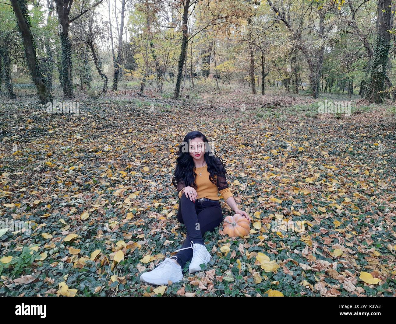 une fille s'étend sur le dos dans la nature avec des feuilles d'automne Banque D'Images