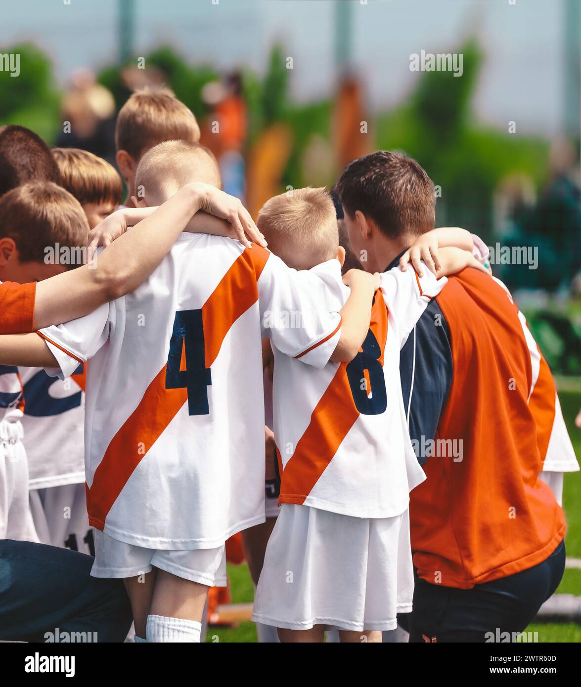 Enfants avec entraîneur dans l'équipe sportive. Amis d'une équipe de football. Joueurs de football masculins se blottissant ensemble dans un cercle avant un match Banque D'Images