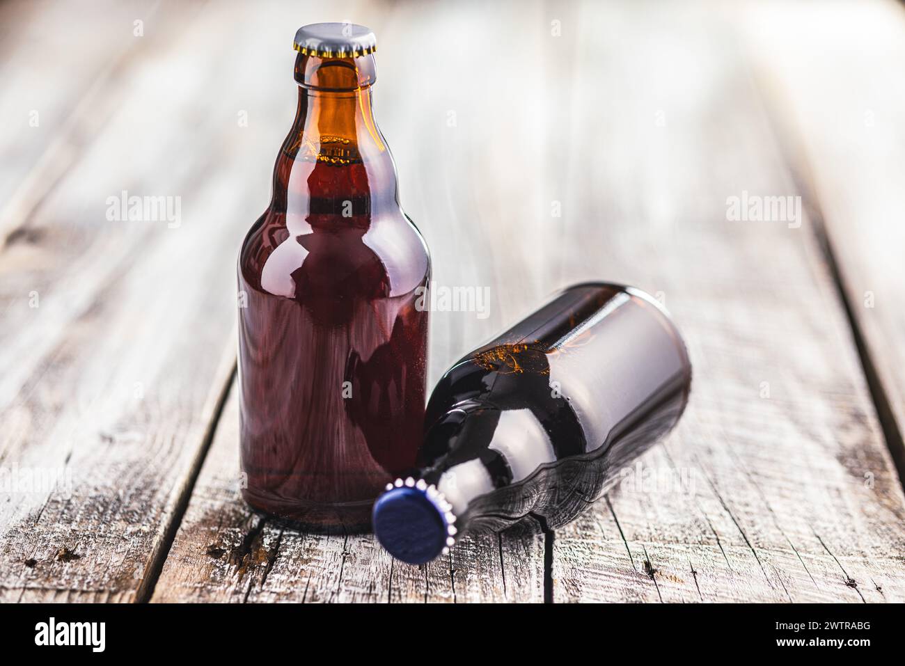 Deux bouteilles en verre brun remplies de bière sont placées sur une table en bois. Banque D'Images