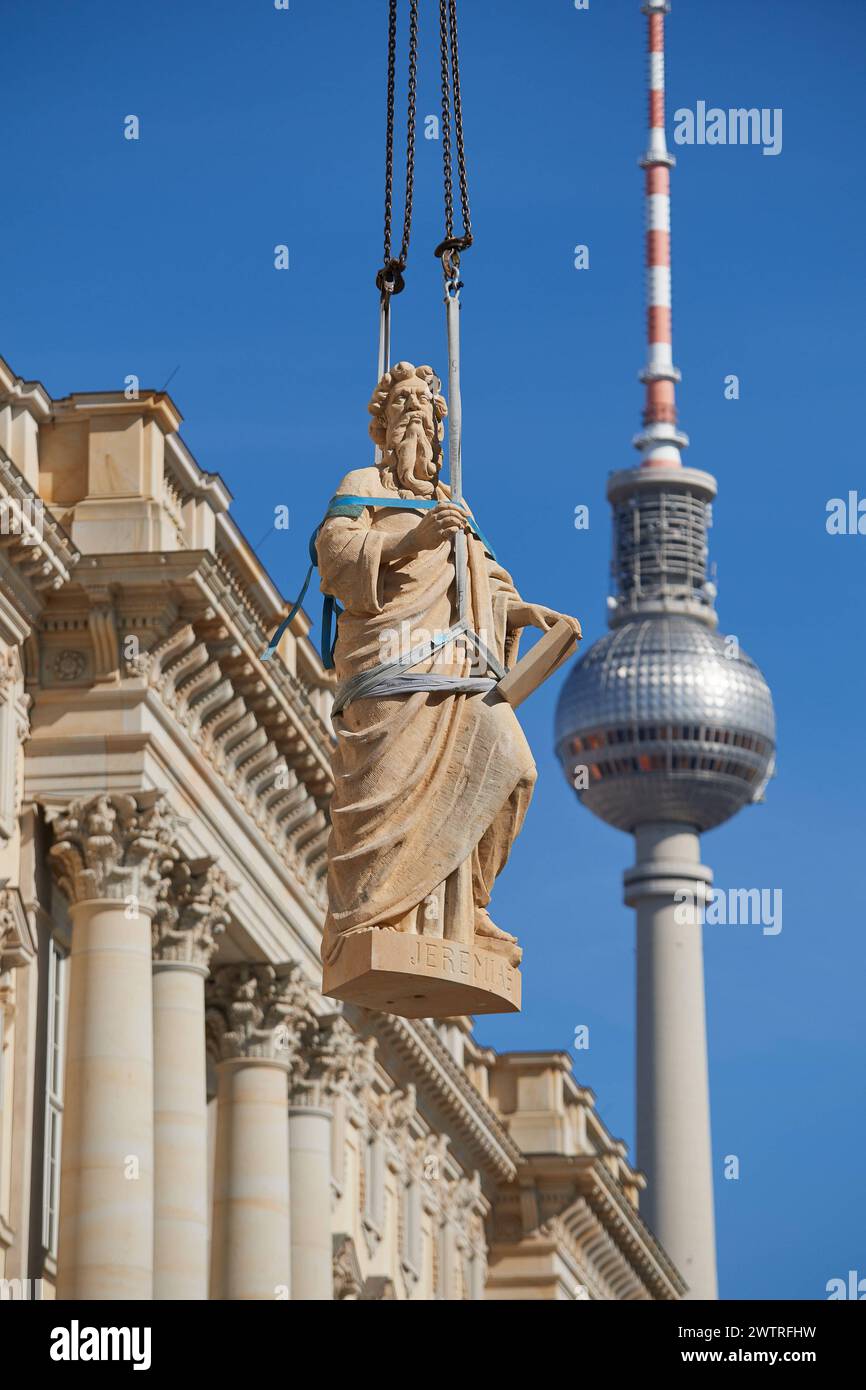 Auf dem Dach des Berliner Humboldt forums stehen seit Dienstag, 19.03.2024, weitere Balustradenskulpturen. Insgesamt sollten acht, jeweils drei Tonnen schwere Propheten-Figuren mit einem Spezialkran aufs Dach gehoben und an der Kuppel-balustrade montiert werden. Bis Dienstagmittag gruesste der Prophet Jeremias vom Dach, wie ein Sprecher der Stiftung Humboldt Forum auf Anfrage mitteilte Foto vom 19.03.2024 : Die figure des Propheten Jeremias wird mit einem Schwerlastkran zur Kuppel gehoben. Die Sandsteinfiguren sind einschliesslich Grundplatte jeweils 3,3 mètres brut, drei Tonnen schwer und haben Banque D'Images