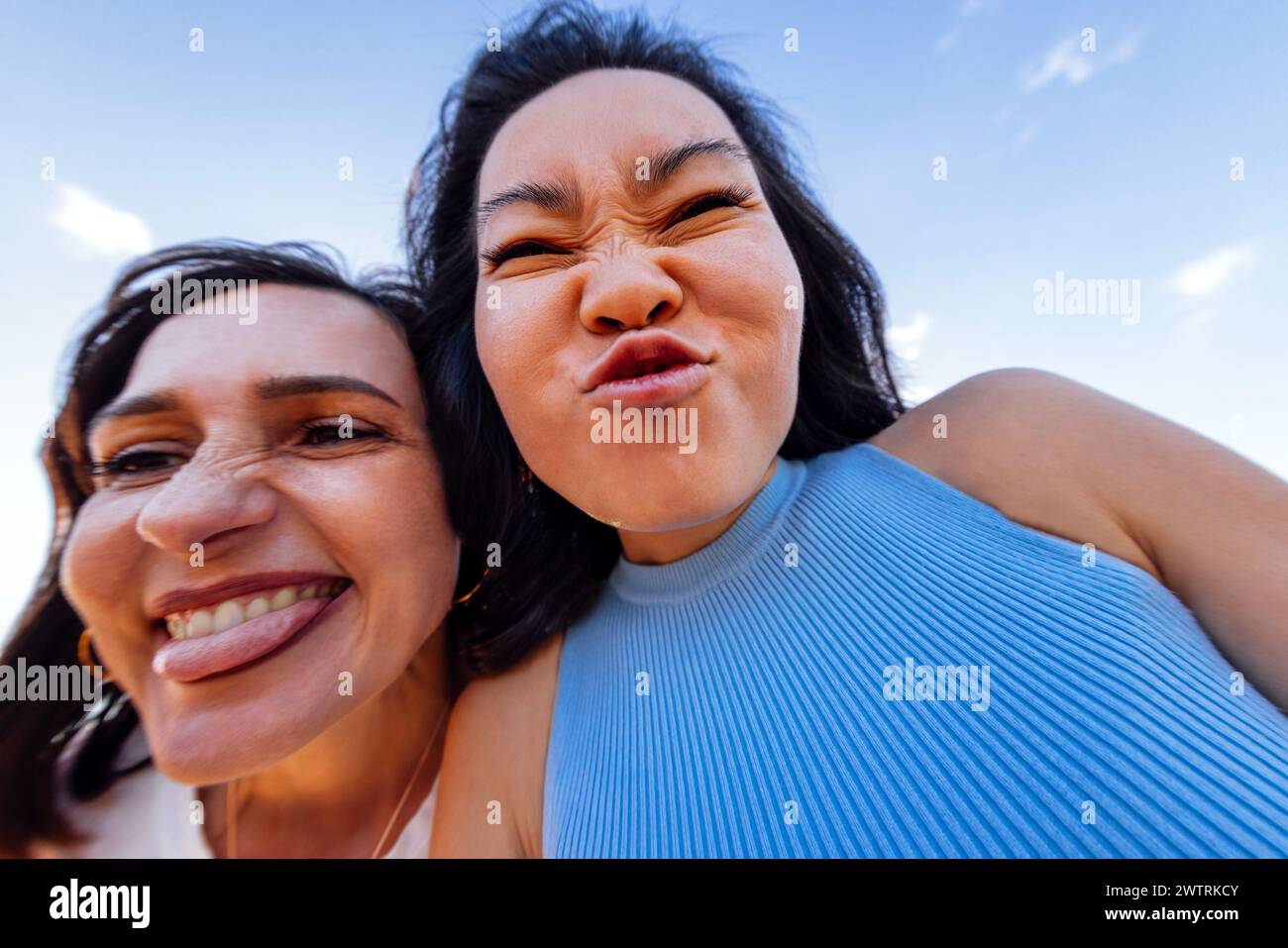 Deux filles mignonnes de différentes races grimace et amusent ensemble. Des amis multiethniques attrayants prennent des selfies drôles à l'extérieur. Gros plan d'un visage riant Banque D'Images