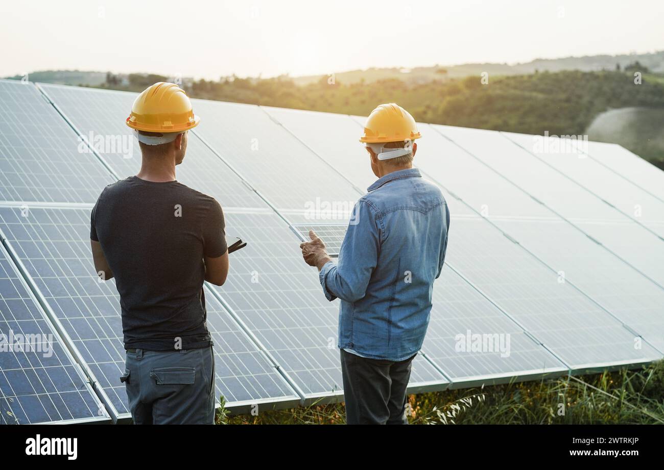 Ingénieurs travaillant à l'usine de panneaux solaires en plein air - photovoltaïque, énergie verte renouvelable et concept environnemental - objectif principal sur la tête de l'homme gauche Banque D'Images