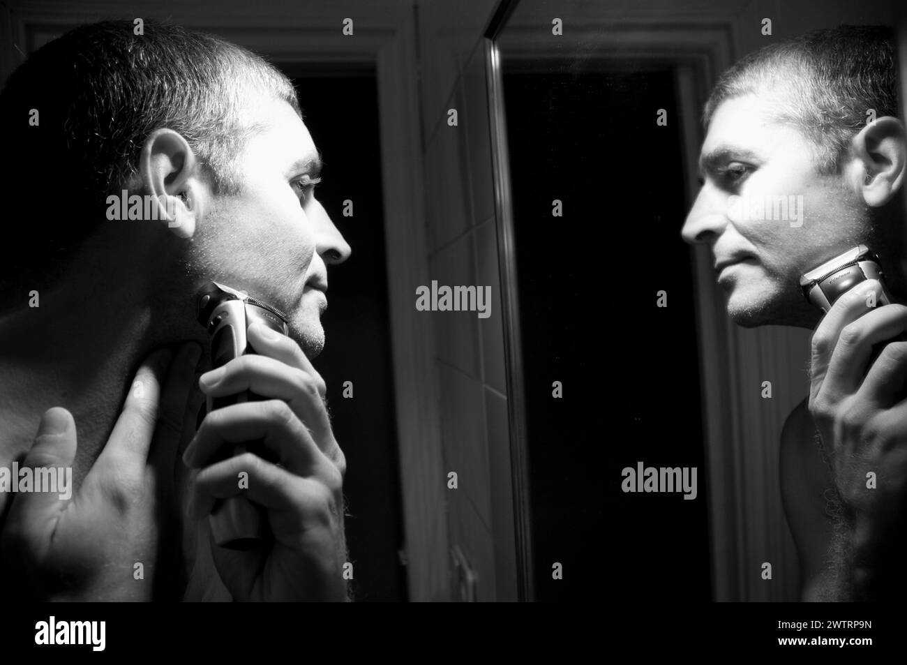 Homme se rasant le visage devant le miroir. Noir et blanc. Banque D'Images