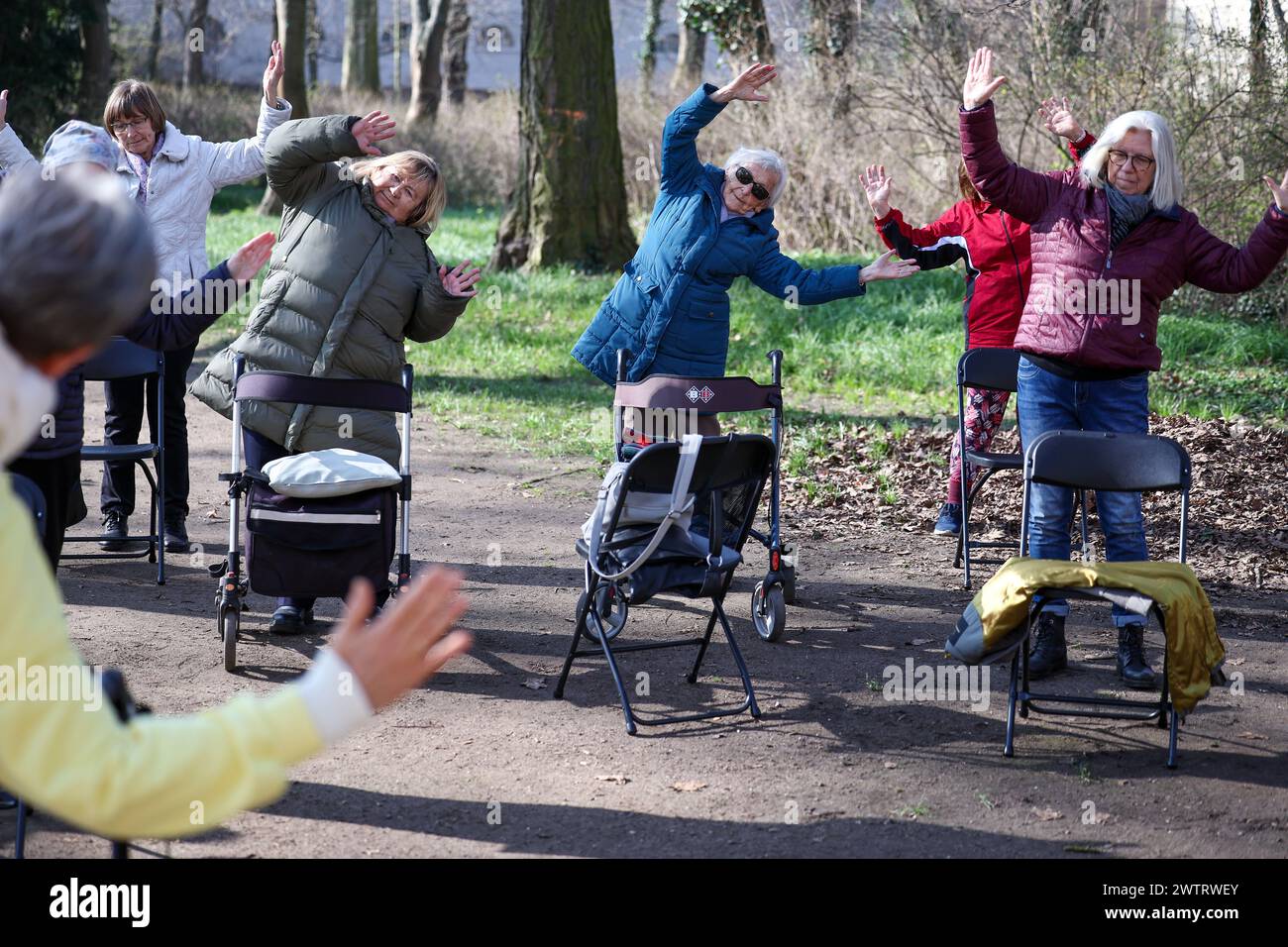PRODUCTION - 13 mars 2024, Saxe-Anhalt, Köthen : les seniors participent à un cours de yoga rollator pour seniors dans le parc du château de Köthen. Le cours propose des exercices ciblés qui peuvent être effectués sur et hors du rollator. Photo : Jan Woitas/dpa Banque D'Images