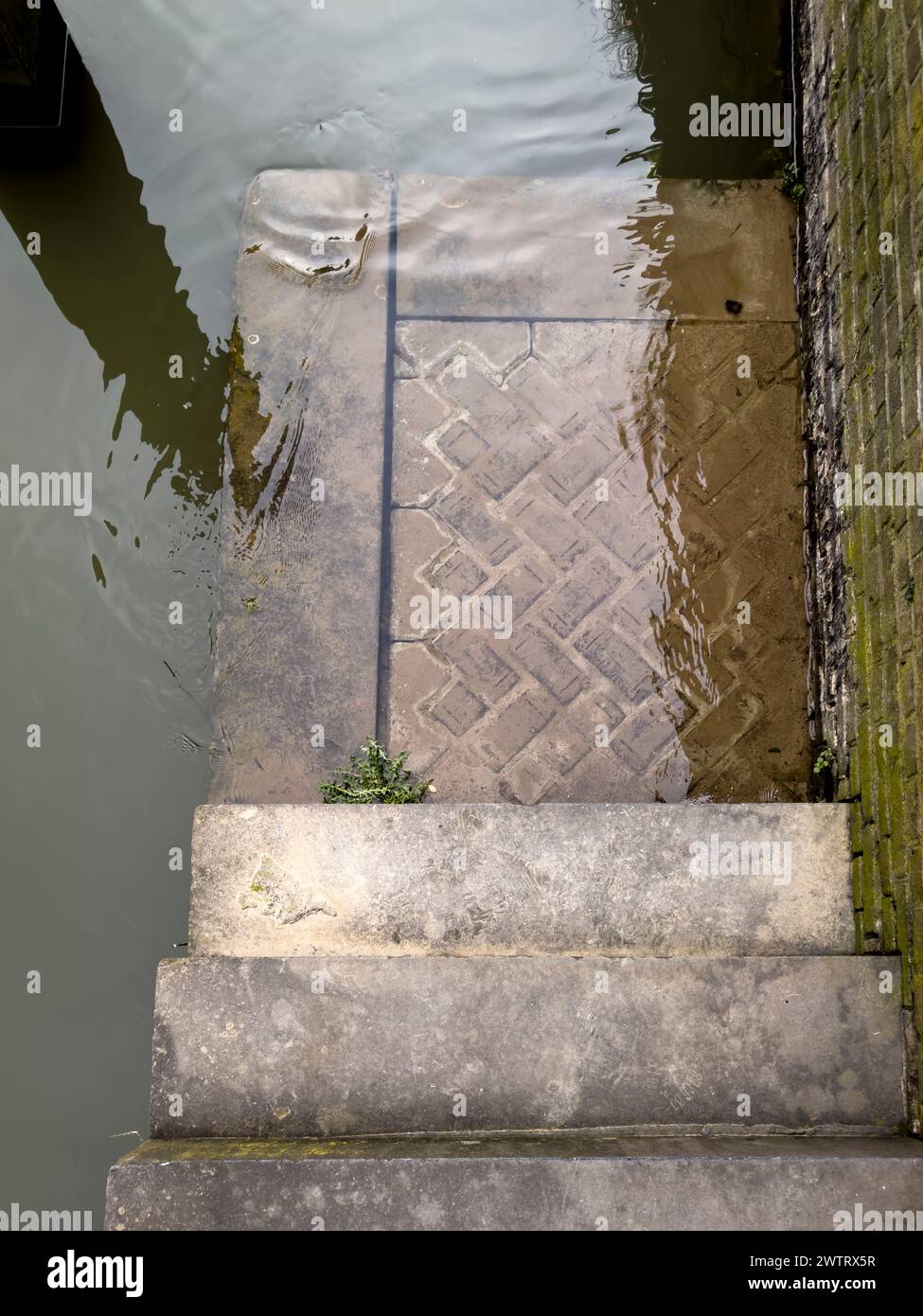 Marches menant au canal urbain hollandais par un jour sombre et pluvieux, encapsulant le charme mélancolique des paysages urbains des pays-Bas. Banque D'Images