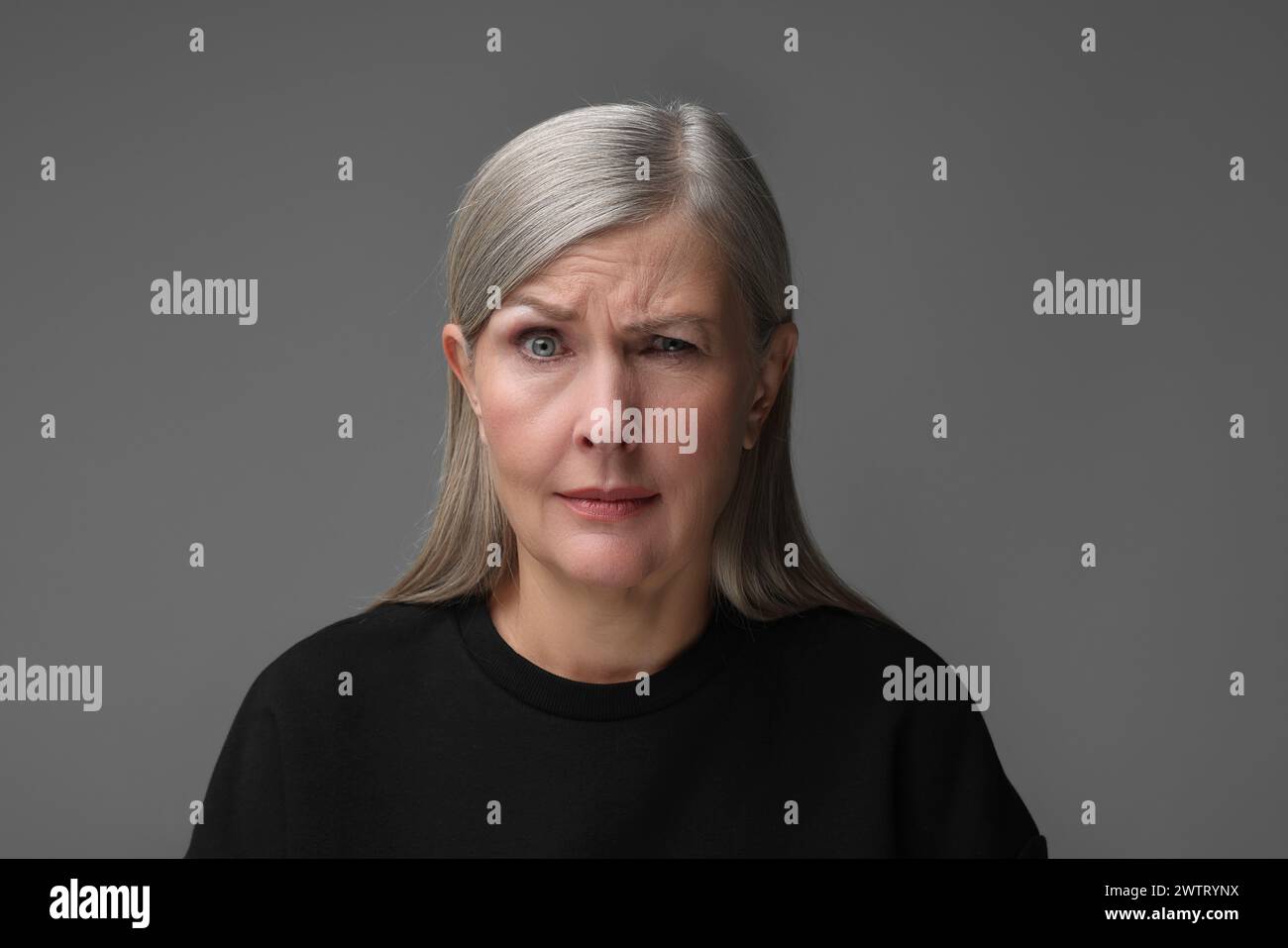 Concept de personnalité. Portrait de femme faisant un clin d'œil sur fond gris Banque D'Images