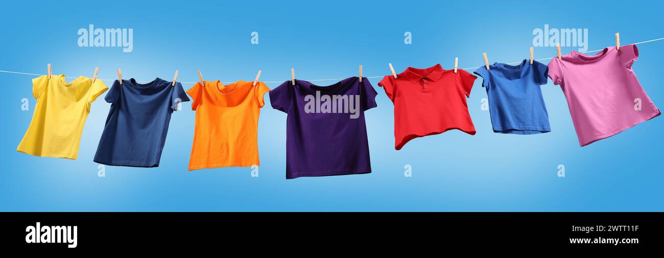 T-shirts colorés séchant sur la ligne de lavage contre le ciel bleu, vue d'angle bas. Conception de bannière Banque D'Images T-shirts colorés séchant sur la ligne de lavage contre le ciel bleu, vue d'angle bas. Conception de bannière Banque D'Images