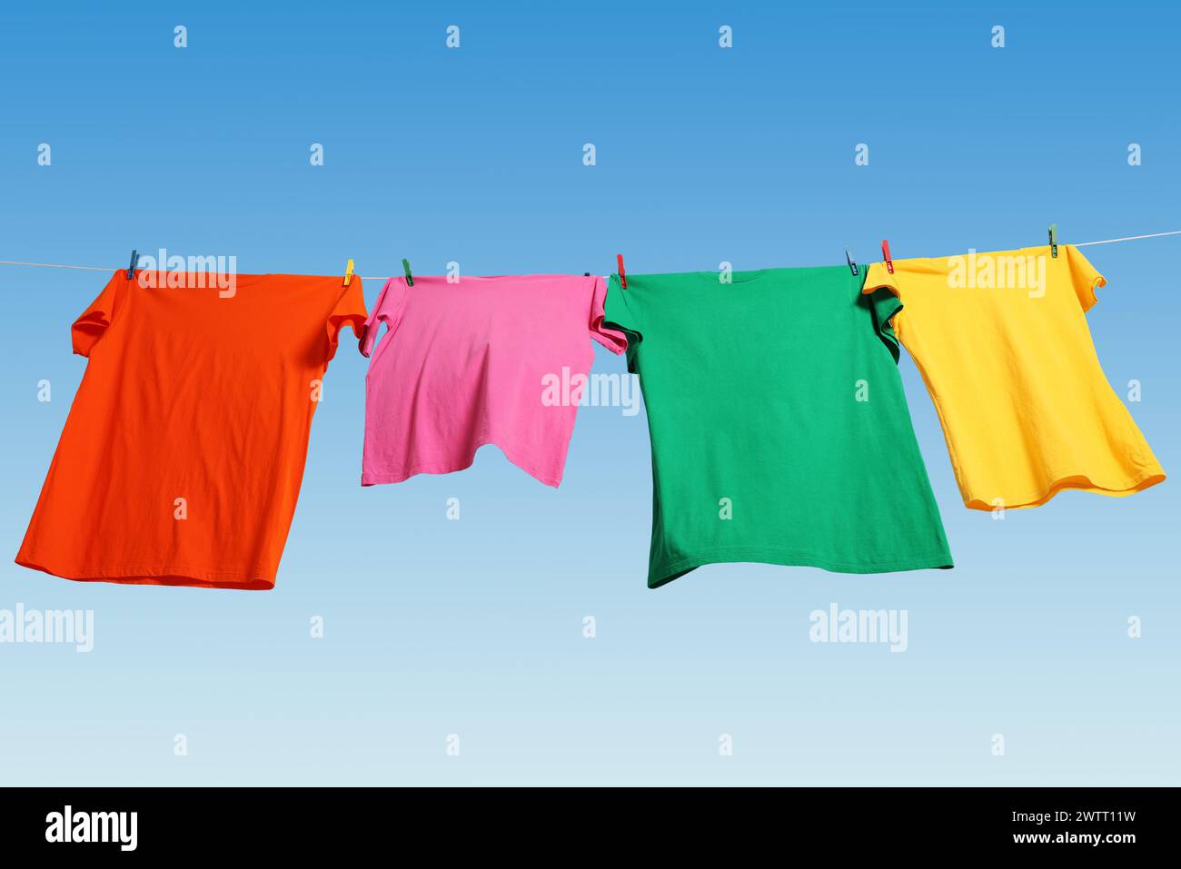 T-shirts colorés séchant sur la ligne de lavage contre le ciel bleu, vue d'angle bas Banque D'Images T-shirts colorés séchant sur la ligne de lavage contre le ciel bleu, vue d'angle bas Banque D'Images