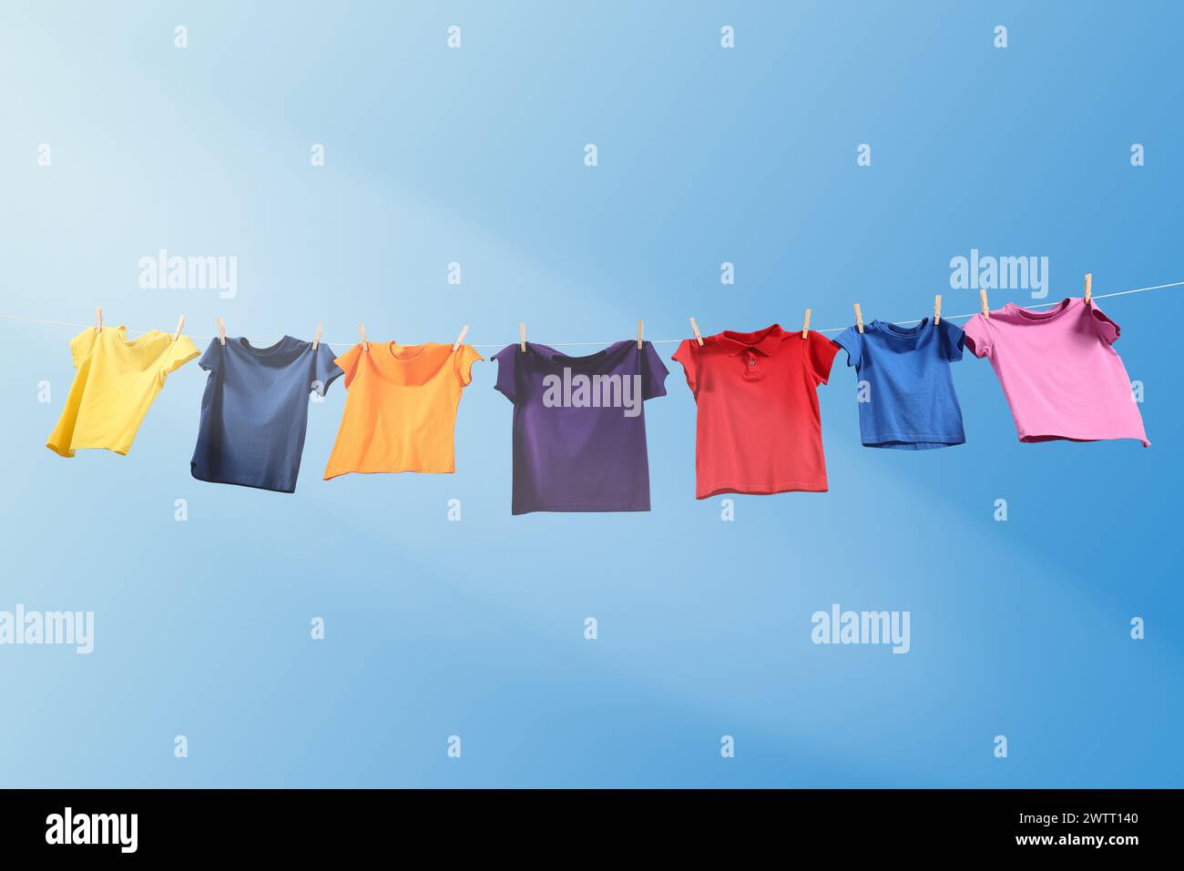 T-shirts colorés séchant sur la ligne de lavage contre le ciel bleu, vue d'angle bas Banque D'Images T-shirts colorés séchant sur la ligne de lavage contre le ciel bleu, vue d'angle bas Banque D'Images