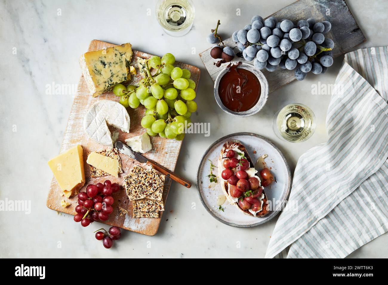 Une assiette gastronomique de fromages et de fruits accompagnée de vin un après-midi tranquille. Banque D'Images