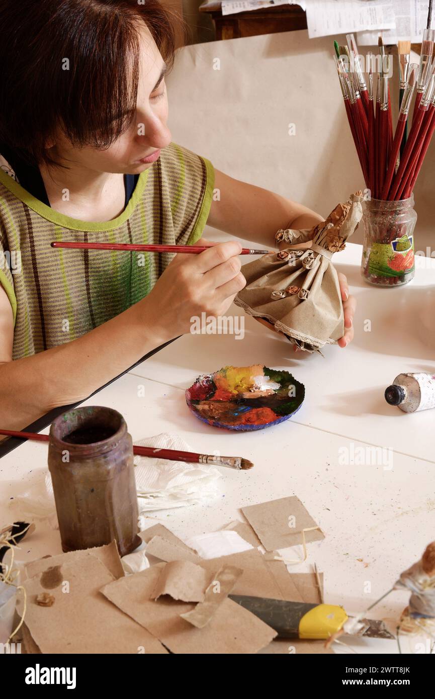 Artiste au travail, peignant méticuleusement une sculpture avec une palette de couleurs à portée de main. Banque D'Images