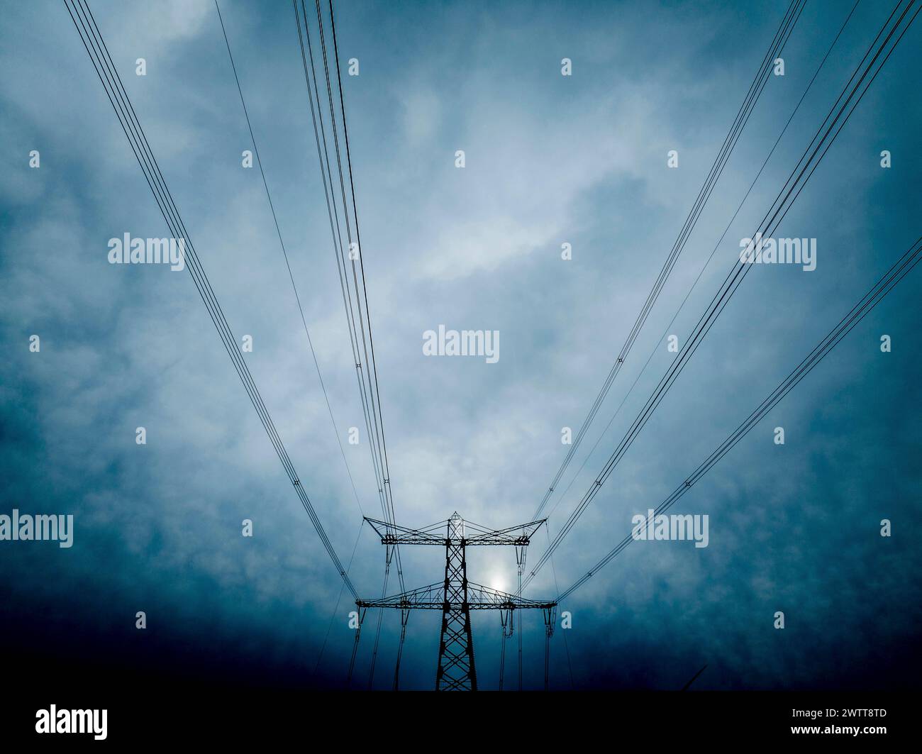 Pylônes électriques atteignant un ciel sombre Banque D'Images