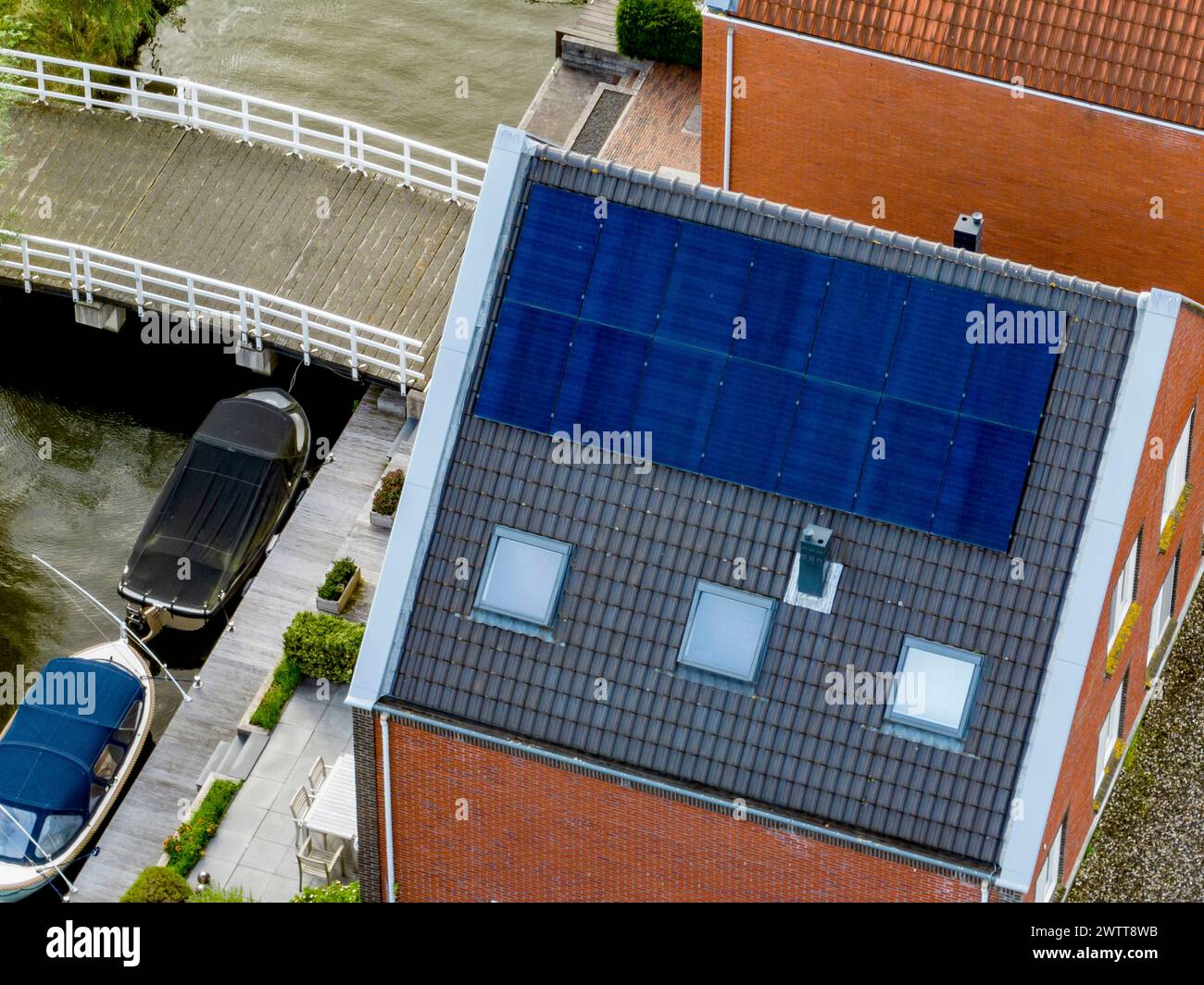 Vue aérienne du quartier résidentiel avec un canal, un bateau et des panneaux solaires sur un toit. Banque D'Images